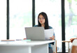 © ijeab - A woman is sitting at a table with a laptop and a piece of paper