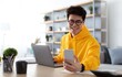 © Prostock-studio - Business And Telecommuting Concept. Portrait of smiling young asian man using smartphone and modern laptop computer, reading text message, sitting at desk with gadgets, working at home office