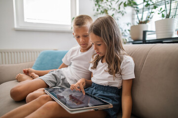 Young siblings using a laptop together on the couch
