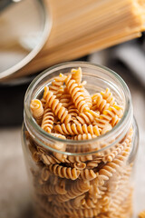 Wall Mural - Uncooked whole grain pasta. Raw fusilli in jar on kitchen table.