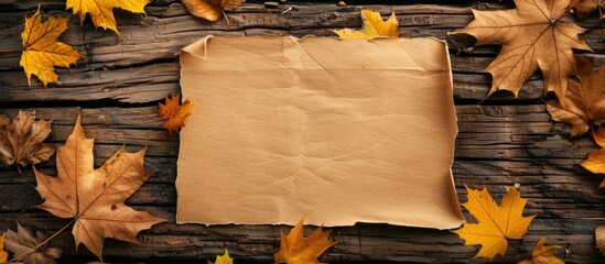 Wall Mural - Autumn themed composition with a blank paper yellow leaves on a wooden surface suitable for text Autumn greeting card with copy space image