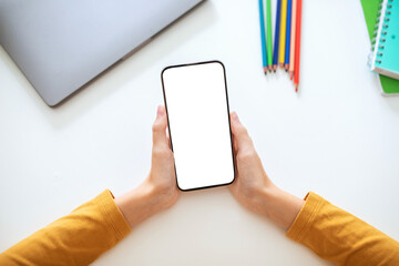 Fototapete - A person is holding a smartphone with a blank screen in their hands. The phone is positioned horizontally, with the screen facing the viewer