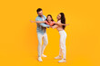 © Prostock-studio - A young girl is being held aloft by her parents as they play airplane on a bright yellow background. The girl is smiling and laughing, and her parents are both looking at her with love