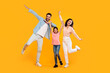 © Prostock-studio - A family of three is posing for a photo in a studio. The father is striking a playful pose with his arm outstretched, while the mother and daughter are jumping and smiling brightly.