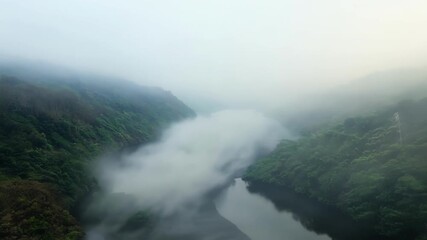 Canvas Print - The fog slowly moves and shifts revealing glimpses of the meandering river beneath and adding a touch of mystery to the footage.