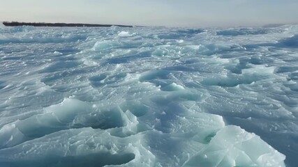 Wall Mural - A mesmerizing aerial shot captures the frozen waves resembling a glimmering mosaic of ice crystals.