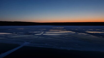 Sticker - The eerie stillness of a frozen lake at twilight with only a faint hint of orange in the sky as night falls.