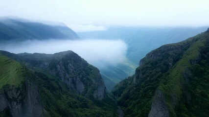 Sticker - Aerial shot of misty mountain valleys with layers of fog cascading down the slopes.