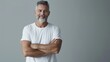 © liliyabatyrova - A man with a white shirt and gray hair is standing with his arms crossed