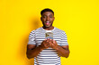 © deagreez - Portrait of nice young man use phone wear striped t-shirt isolated on vibrant yellow color background