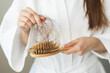 © KMPZZZ - Stress asian young woman, girl hand holding comb show her hairbrush with loss, hair in brush after brushing, hair fall out problem. Health care, beauty with treatment concept, isolated on background.