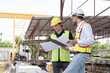 © amorn - Team of male engineer construction working and inspecting structure of building at construction site. Two male construction builder working at construction site