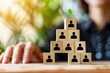 © Worrapol - Growing Together: A symbolic image of wooden blocks with people icons arranged in a pyramid, representing growth, collaboration, and a strong foundation for success.  A single green sprout on top symb