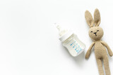 Fototapeta Tulipany - Feeding time for baby. Milk in bottle with toy on white background, top view