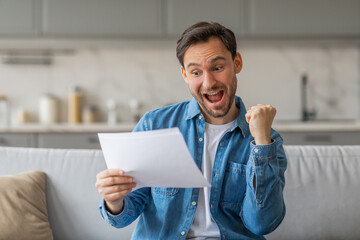 Poster - A man holding a piece of paper and reading it with an excited expression. He has a big smile on his face and his right fist is clenched in the air. He appears to have just received some good news