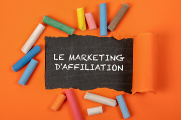 Wall Mural - affiliate marketing. text in french . text under torn orange paper on a blackboar