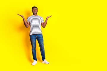 Full size photo of nice young man hold empty space vs wear t-shirt isolated on bright yellow color background