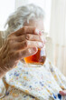 © berna_namoglu - wrinkled hand of senior woman holds glass of tea