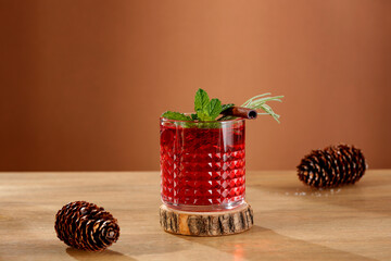 Poster - Red fruit cold brew water drink with fresh rosemary and mint leaves in glass on wooden table and  brown background. 