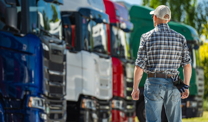 Truck Driver Inspecting Fleet of Colorful Trucks at Transportation Yard