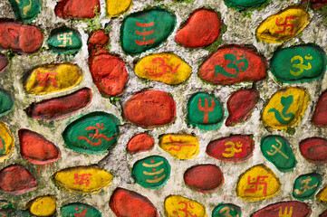 Wall Mural - Colourful Hindu religious symbols painted on colourful stones, sacred symbols of traditional Hinduism. The walls at side of way to Mahakal Temple, ancient Hindu temple at Darjeeling,West Bengal,India.