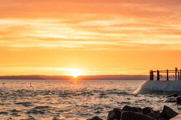 Wall Mural - a small marina on a lake. Breakwater and pillar with golden figure in the dreamy sunset. Landscape shot in Siófok, Balaton, Hungary