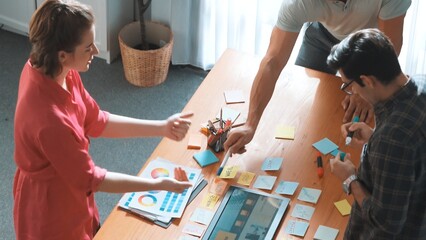 Top view of manager writing idea on sticky notes and explain idea about web design. Professional marketing team or programmer brainstorming idea while looking at tablet with color palette. Symposium.