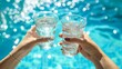 © Taisiia - A glass of clean water in hands against the background of the pool