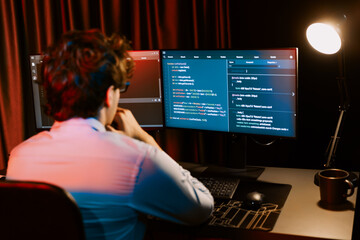 Working IT developer concentrating online software development information on surrounded by coding application pc screens, creating program for firmware on website at neon modern office home. Gusher.