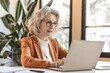 © Maria Vitkovska - Confident senior businesswoman working on laptop in office