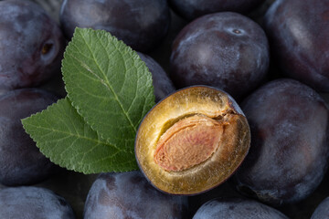 Wall Mural - Half ripe plum fruit with leaves closeup on heap whole organic fresh fruits. Healthy food.