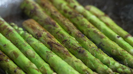 Grilled asparagus spears sizzling in a pan, showcasing vibrant green color and caramelized edges, perfect for culinary and food photography enthusiasts looking for fresh vegetable imagery