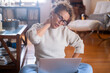 © simona - One adult woman suffering from neck ache after working with laptop computer in bad posture sitting on the floor at home. Massaging for painful neckache at home middle age lady. Tired people overwork