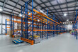 © alhim - Modern Warehouse Interior Featuring Tall Shelving Units and Stored Goods. This spacious warehouse showcases an organized interior with towering shelving units filled with pallets of various products.