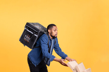 Poster - Reckless african american courier spilling a lot of pizza in studio, dropping massive pile of boxes and making a mess. Deliveryman being clumsy and causing an accident, wasting food.