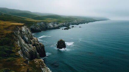 Fototapete - A rocky shoreline with a body of water in the background. The water is calm and the sky is overcast