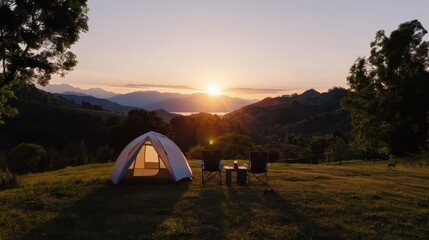 Poster - A white tent is set up in a grassy field with a view of the mountains. The sun is setting, casting a warm glow over the scene. There are two chairs and a table nearby