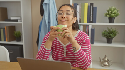 Poster - A relaxed hispanic woman enjoys a coffee break at home, surrounded by plants and books.