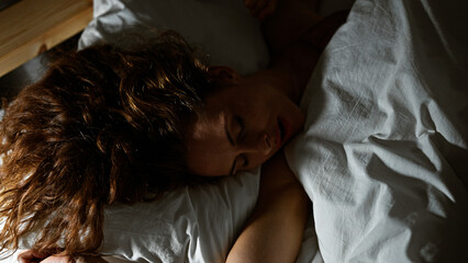 Poster - A young caucasian woman rests peacefully in a bedroom, depicting comfort and relaxation in a home interior scene.