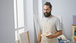 © Krakenimages.com - Handsome hispanic man with a beard, in an apron, holds a palette in an art studio.