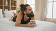 © Krakenimages.com - A bearded young man relaxes in a bedroom with a coffee, embodying leisure and comfort in a casual setting.