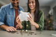 © Miljan Živković - Adult couple save money coins in the piggy bank at home