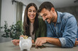 © Miljan Živković - Adult couple save money coins in the piggy bank at home