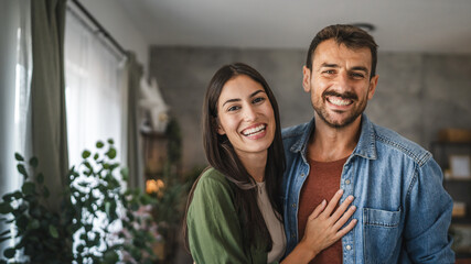 Portrait of beautiful couple stand, smile and hug at home