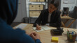 © Krakenimages.com - Woman investigator interrogates a man in an office, with passports and a notepad on the desk.
