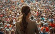 © imagineRbc - A woman speaks passionately to a large crowd gathered in a public park, energized by her message during a political rally