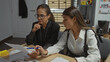 © Krakenimages.com - Two women scrutinize documents, embodying detectives in an office setting, hinting at an investigation underway.