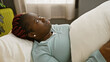 © Krakenimages.com - Black woman with braids lying on a white pillow at a rehab clinic room, looking pensive and relaxed.