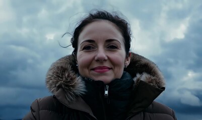 Wall Mural - Portrait of a beautiful woman in a winter jacket on the background of cloudy sky