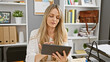 © Krakenimages.com - A focused young woman in an office examines a tablet by a bookshelf and plants, illustrating modern work life.